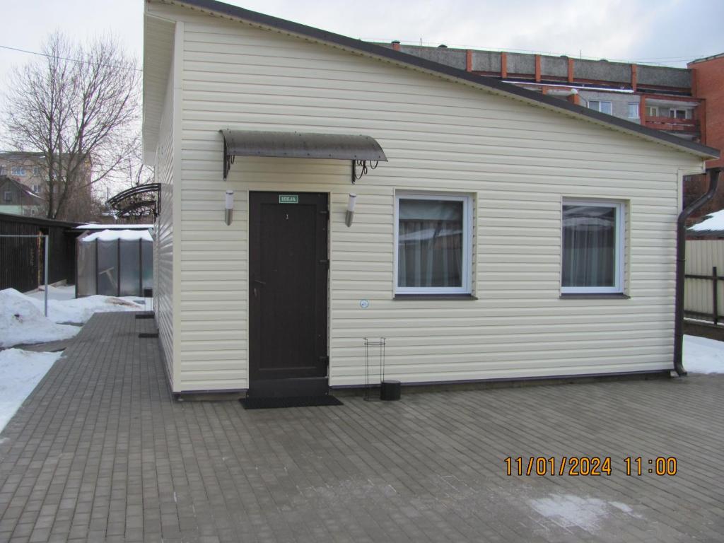 une petite maison blanche avec une porte noire dans l'établissement ziedu pasaule 2, à Krāslava