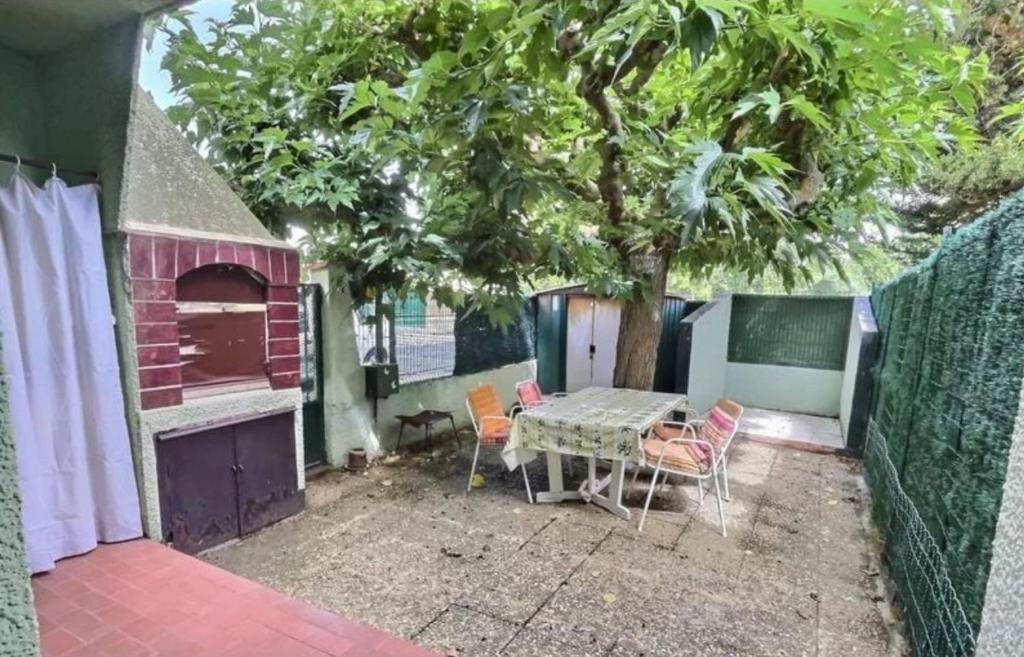 d'une terrasse avec une table, des chaises et un arbre. dans l'établissement Guti, à Valras-Plage