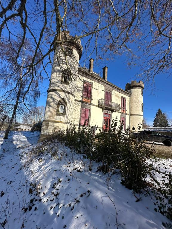 an old stone house with red windows in the snow at Le Château Giat in Giat