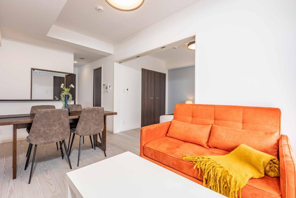 FDS Plaisir في أوساكا: غرفة معيشة مع أريكة برتقالية وطاولة