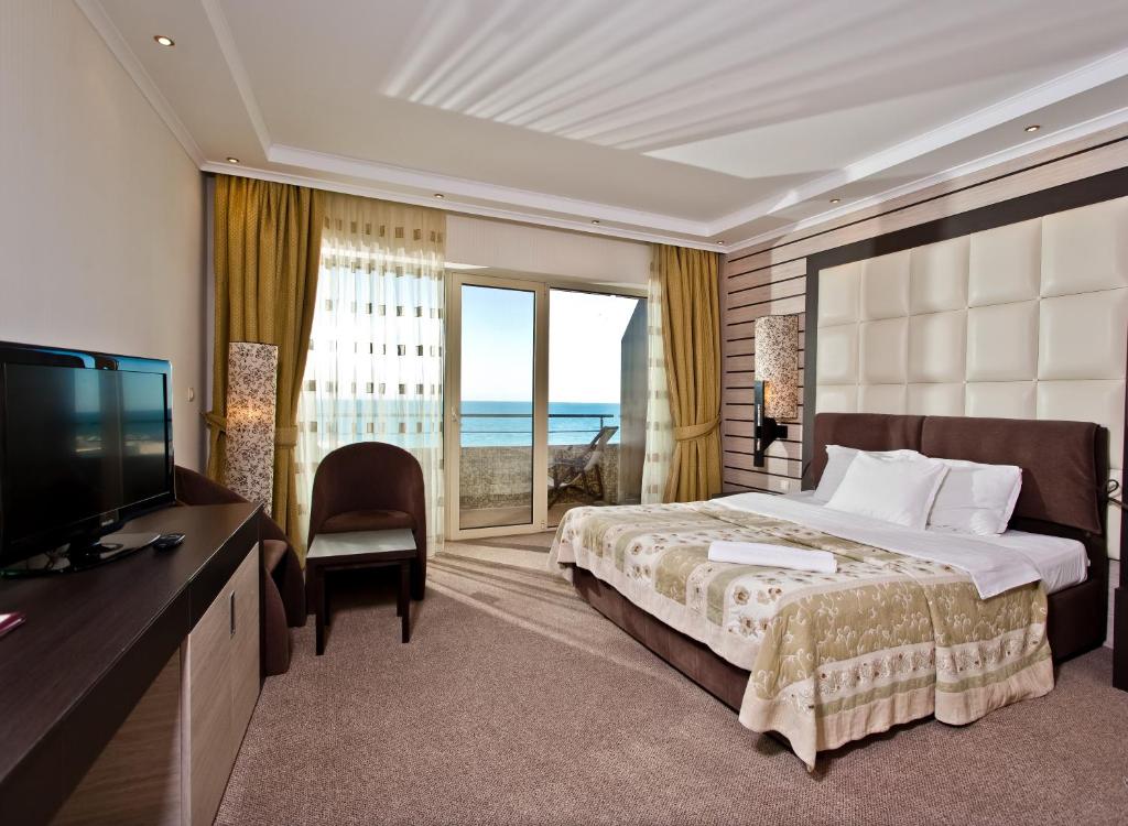 a hotel room with a bed and a tv and a window at Grand Hotel Pomorie in Pomorie