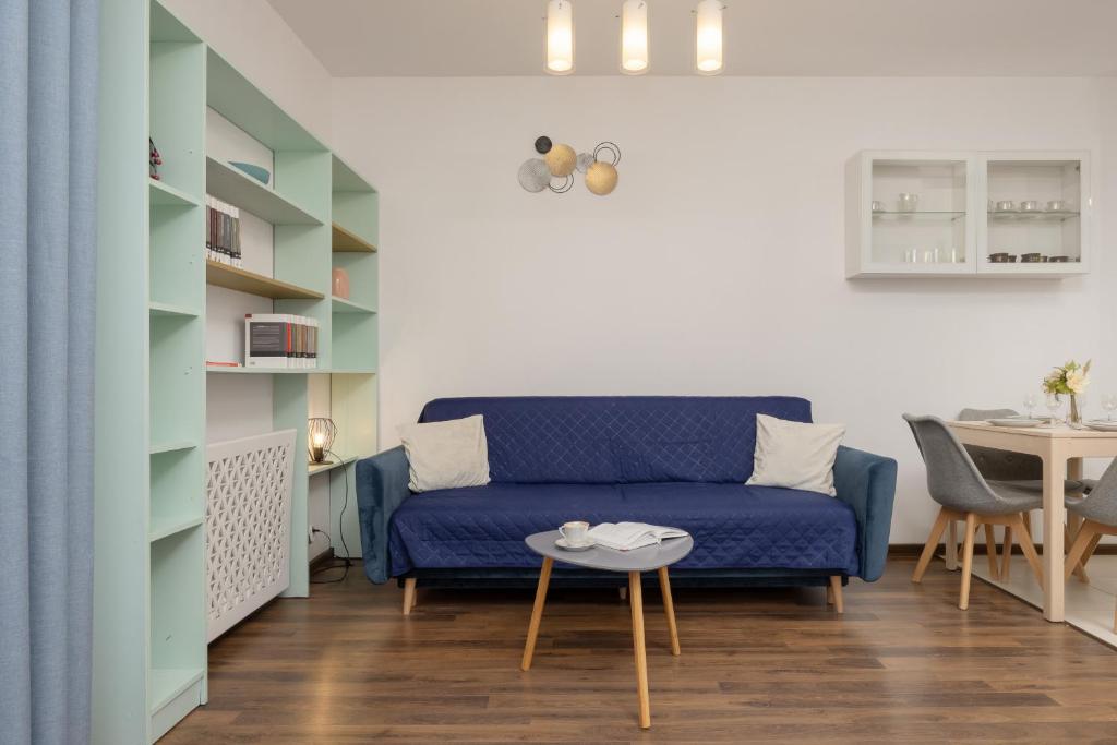 a living room with a blue couch and a table at Trzy Żagle - City View Apartments with Balcony by Renters in Gdańsk