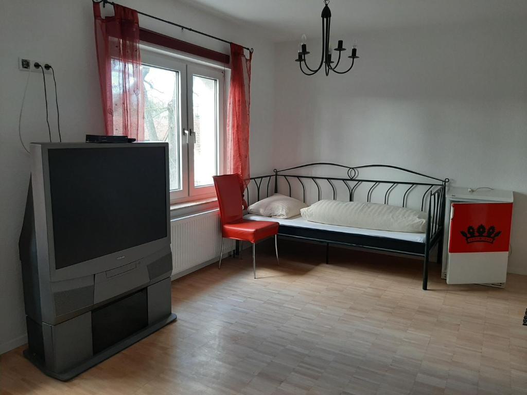 a bedroom with a bed and a tv and a chair at Gasthaus Wendischbrome in Nettgau