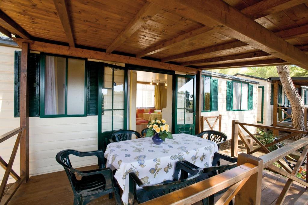 Camping Villaggio Santa Maria Di Leuca في غاليانو دل كابو: شرفة مفتوحة مع طاولة وكراسي