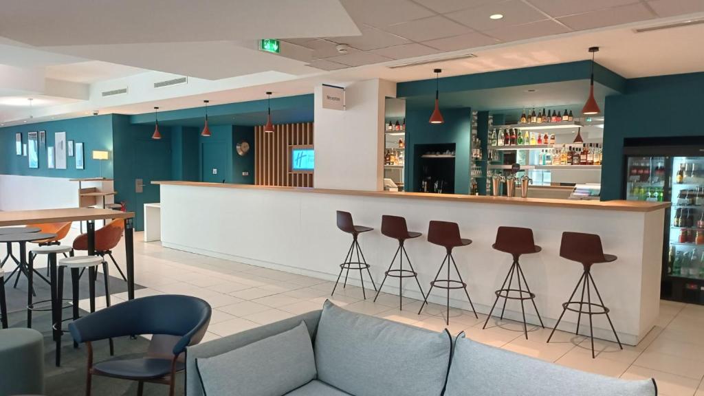 a bar in a restaurant with a couch and stools at Holiday Inn Express Lille Centre, an IHG Hotel in Lille