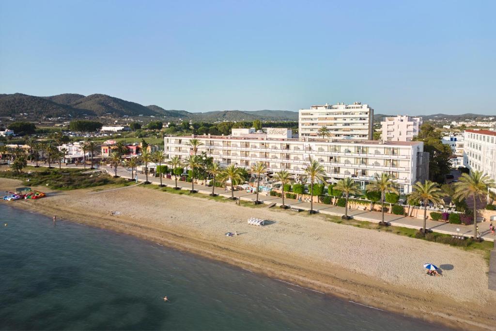 eine Luftansicht auf einen Strand mit Gebäuden und Palmen in der Unterkunft Hotel Arenal in Sant Antoni de Portmany