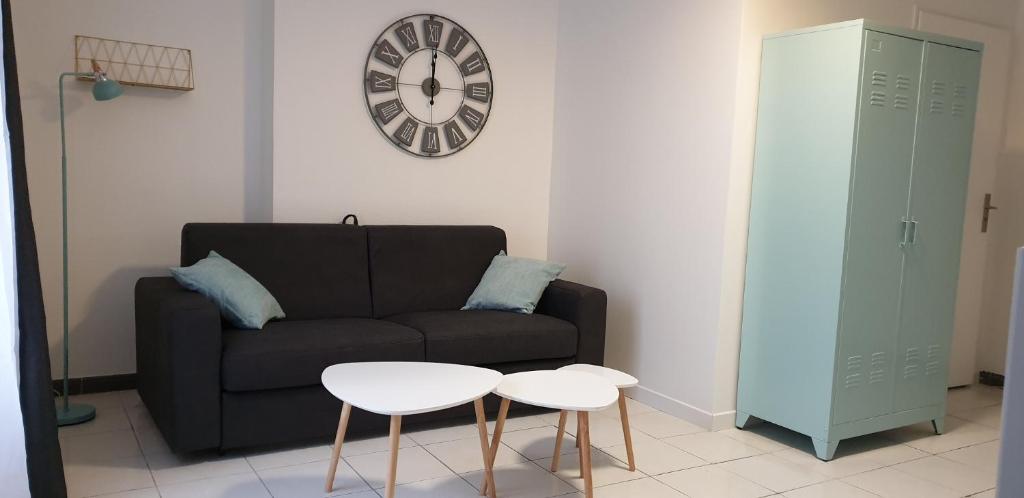 un salon avec un canapé et une horloge au mur dans l'établissement Studio Sablard, à Limoges