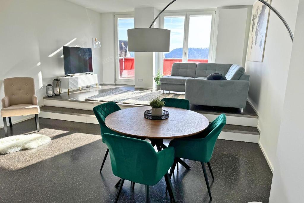 a living room with a table and green chairs at Isaak Appartment Stadtjuwel in Waldshut-Tiengen