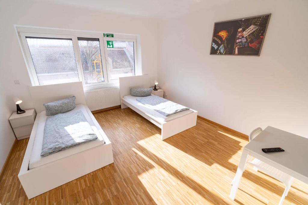 Habitación blanca con 2 camas y mesa en ATRIUM - moderne, großzügige Wohnung 1OG MARIE, en Ludwigshafen am Rhein