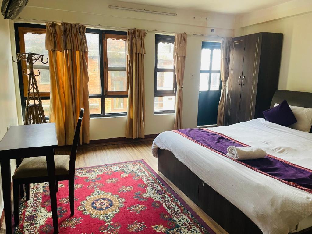 a bedroom with a bed and a desk and windows at Hotel Bhaktapur Inn in Bhaktapur