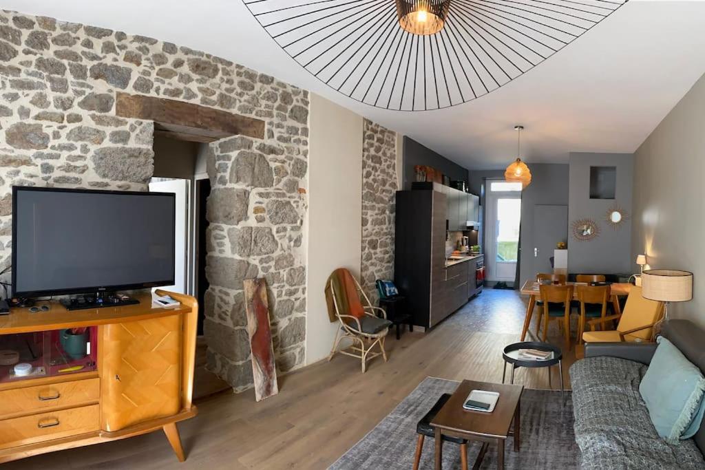 un salon avec une télévision et un mur en pierre dans l'établissement Appartement à 30m de la plage du Sillon., à Saint-Malo
