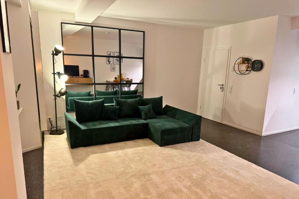 a living room with a green couch and a mirror at Isaak Apartment Stadtperle in Waldshut-Tiengen