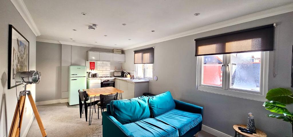 a living room with a blue couch and a kitchen at Victoria House by Switchback Stays in Cardiff