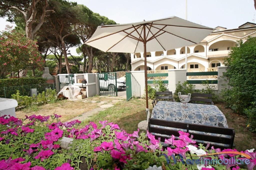 einen Tisch und einen Sonnenschirm in einem Garten mit Blumen in der Unterkunft Navigatore in Marina di Grosseto
