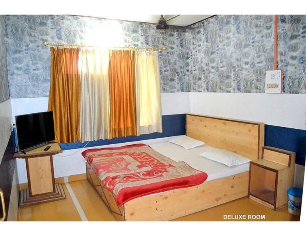 a bedroom with a bed and a television in it at Hotel Royal, Pachmarhi in Pachmarhī