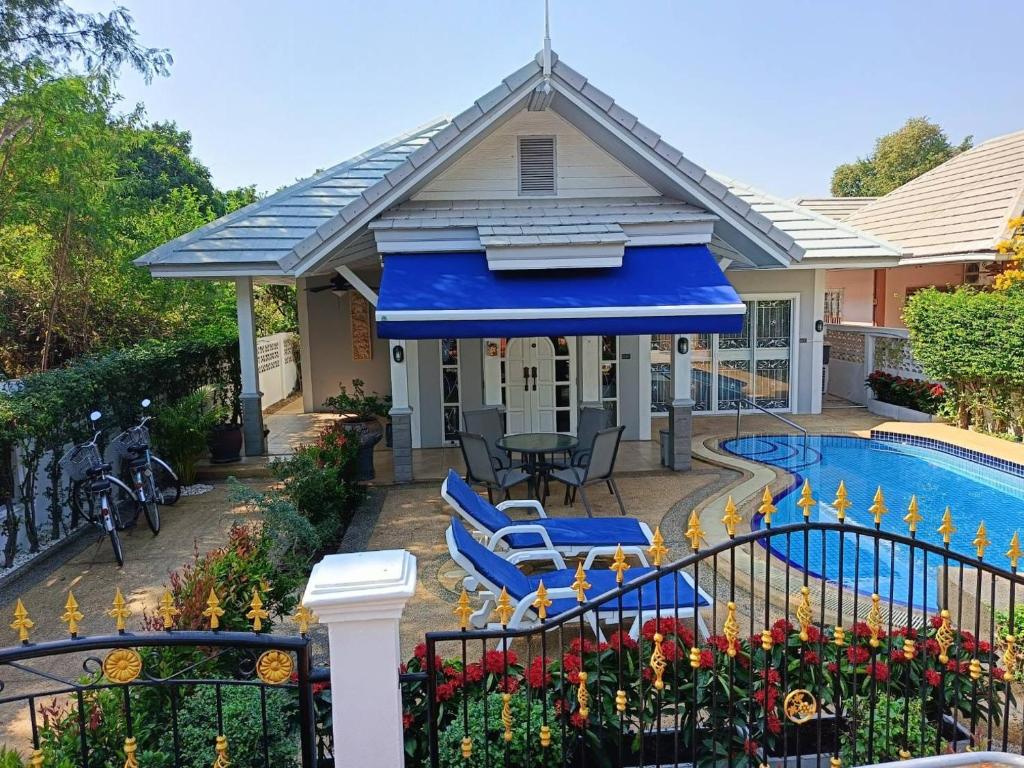 ein Haus mit einem blauen Regenschirm und einem Pool in der Unterkunft Beautiful Villa with private pool in Cha-Am in Ban Sahakham