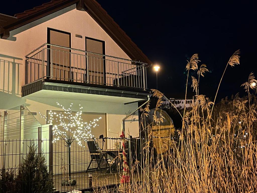 ein Haus mit einem Balkon, einem Tisch und Stühlen in der Unterkunft Villa di Lago - Ferienhaus mit Sauna in Mücheln