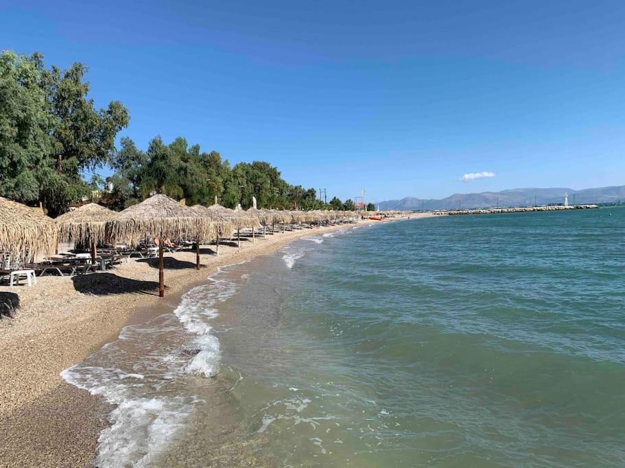 Stylish maisonette only 2min walk to the beach في كيفيريون: شاطئ به مظلات القش والكراسي والماء