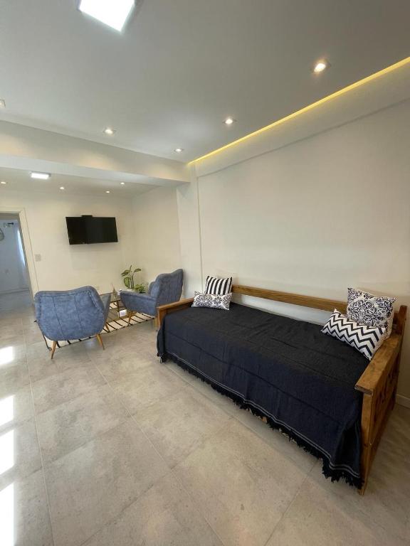 a bedroom with a bed and two chairs and a tv at Patagonia House - Peña in Puerto Madryn