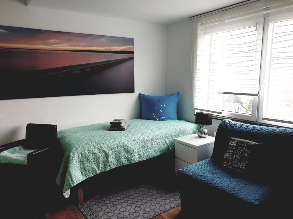 a bedroom with a bed and a chair and a painting at FEWO Solingen Abendstrasse in Solingen