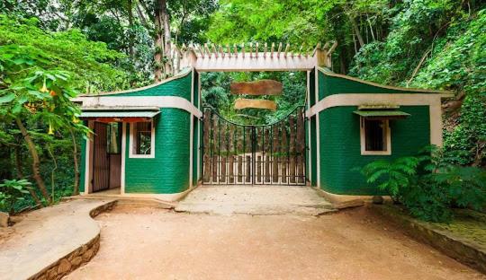 a green house with a gate in a forest at Sakura hotel and restaurant in Kandy