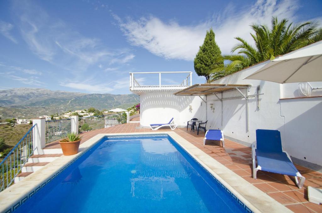 a swimming pool with chairs and a house at Cortijo Bellavista in Cómpeta