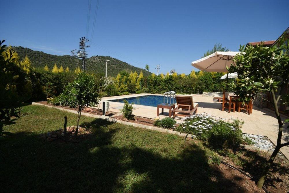 a backyard with a swimming pool and an umbrella at Kilim Kaya Villas in Kınalı