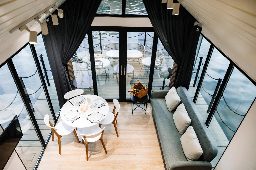 Cette chambre comprend une table, des chaises et des fenêtres. dans l'établissement Dom Na Wodzie La Mare Houseboat, à Bydgoszcz