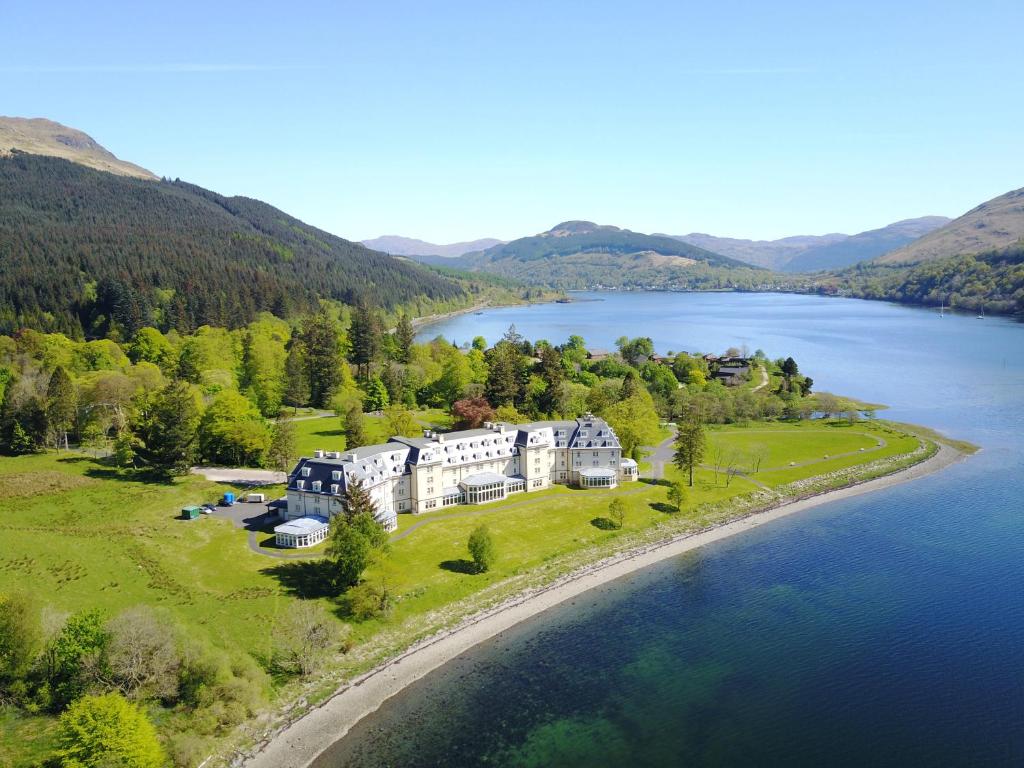 an aerial view of a large house on the shore of a lake at Ardgartan Hotel in Arrochar