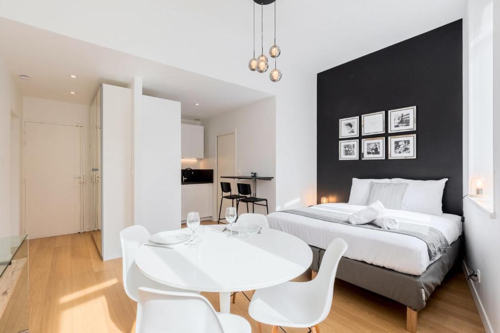 - une chambre avec un lit blanc et une table et des chaises blanches dans l'établissement Vieux Lille - Neat and bright apartment, à Lille