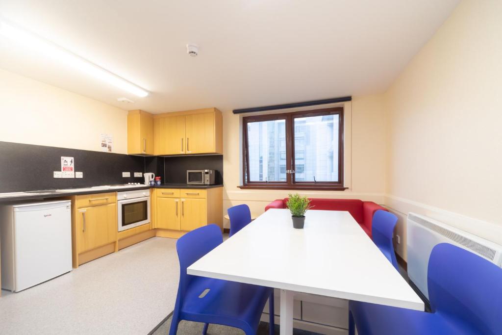 eine Küche mit einem weißen Tisch und blauen Stühlen in der Unterkunft ALTIDO Economy 4 and 5 bed flats, close to Old Town and Royal Mile in Edinburgh