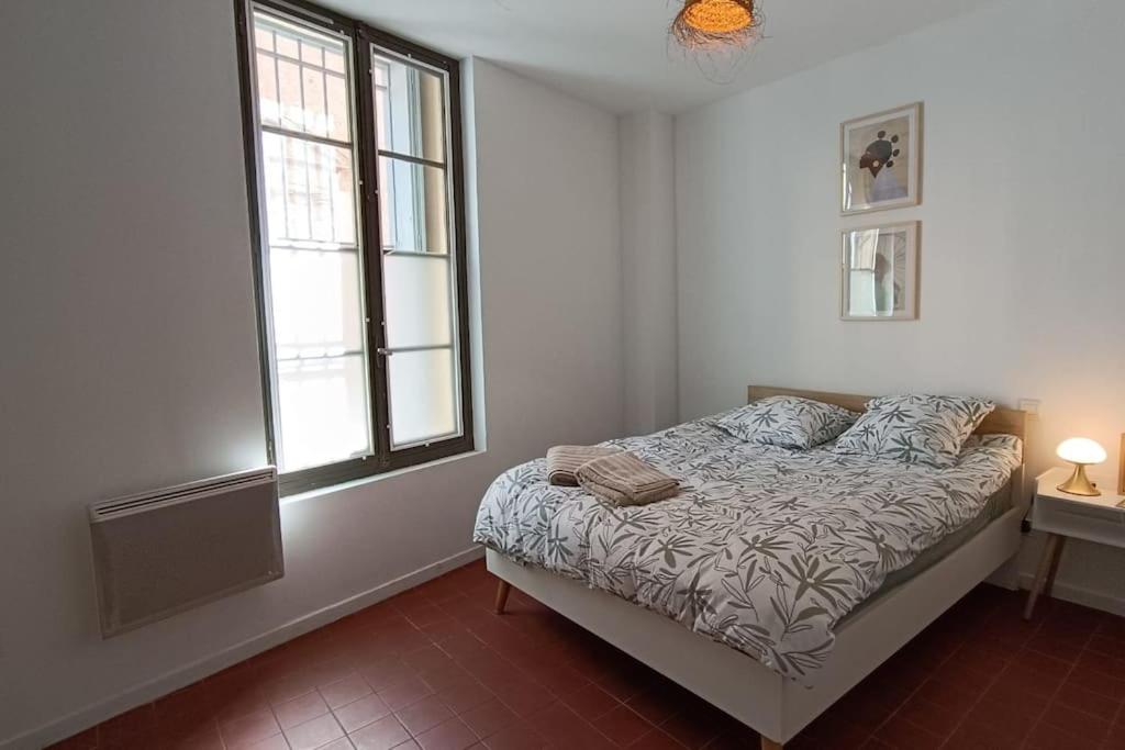 a white bedroom with a bed and a window at hypercentre, appartement coquet en rez-de-chaussée in Perpignan