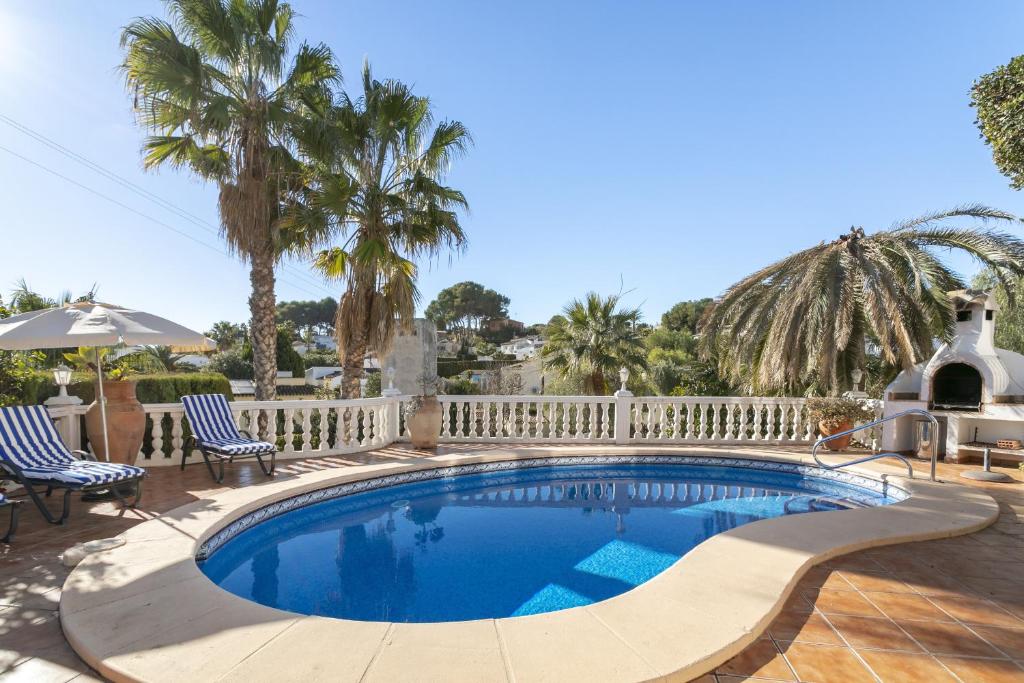 una piscina con recinzione bianca e palme di Villa Piscine à la Fustera, Benissa a Benissa