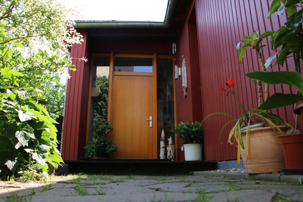 ein rotes Haus mit brauner Tür und einigen Pflanzen in der Unterkunft Gartenhaus Klotzsche in Dresden