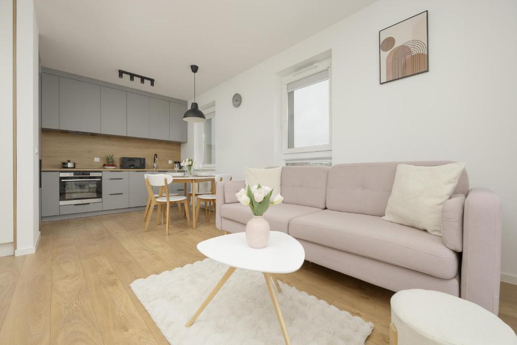 ein weißes Wohnzimmer mit einem Sofa und einem Tisch in der Unterkunft Bright Pastel Apartment with Desk for Remote Work, Balcony and Parking by Renters in Danzig