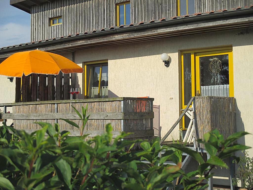 Ferienhaus Poggenkrug Halbsguth في فولغاست: منزل مع شرفة مع مظلة برتقالية