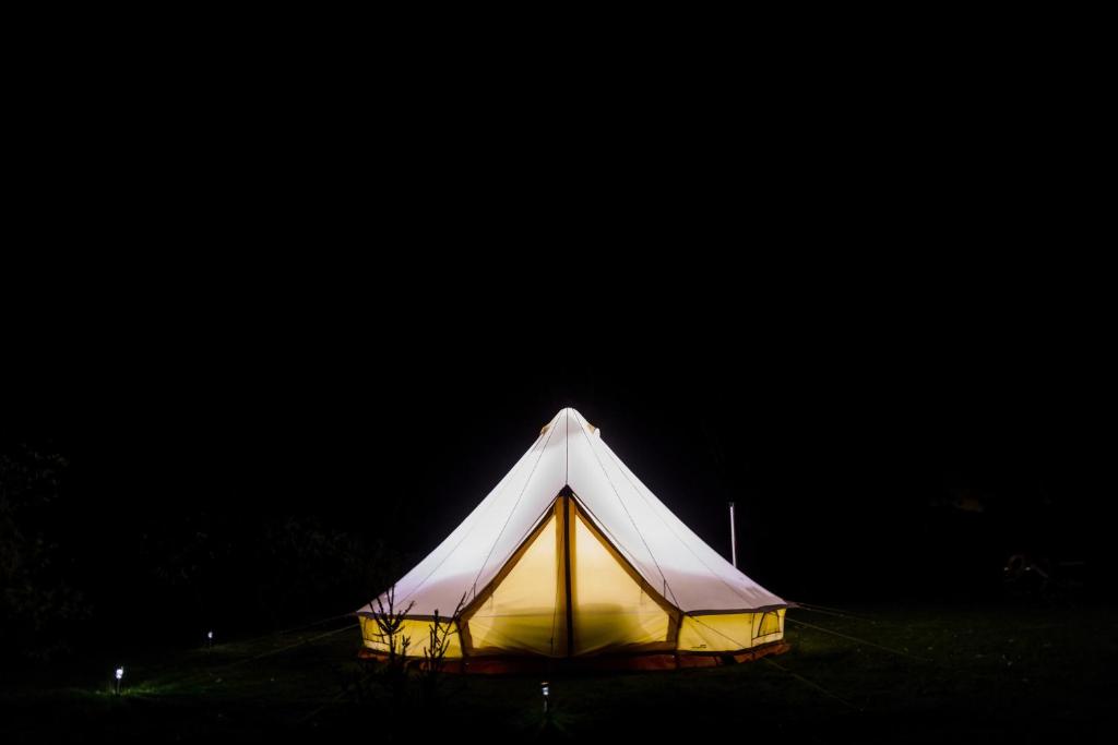 a white tent is lit up at night at Goldfield Glamping in Clydesdale