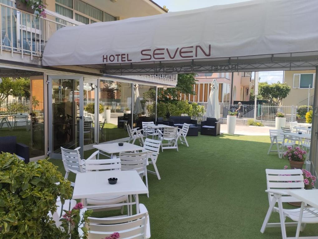 un ristorante con tavoli e sedie bianchi sull'erba di Hotel Seven a Rimini