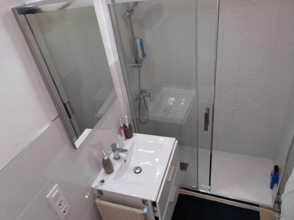 a white bathroom with a sink and a shower at MAGNIFICO PISO JUNTO A PLAYA DE REGLA in Chipiona