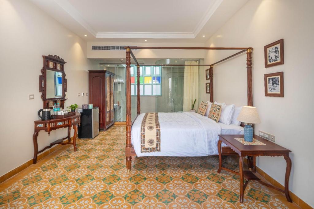 a bedroom with a large bed and a table at Villa Kouga in Puducherry