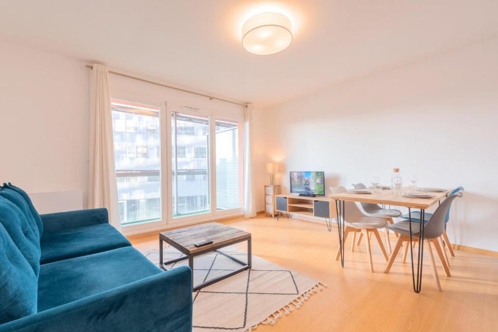 een woonkamer met een blauwe bank en een tafel bij Spacious apartment with parking and balcony! in Lille