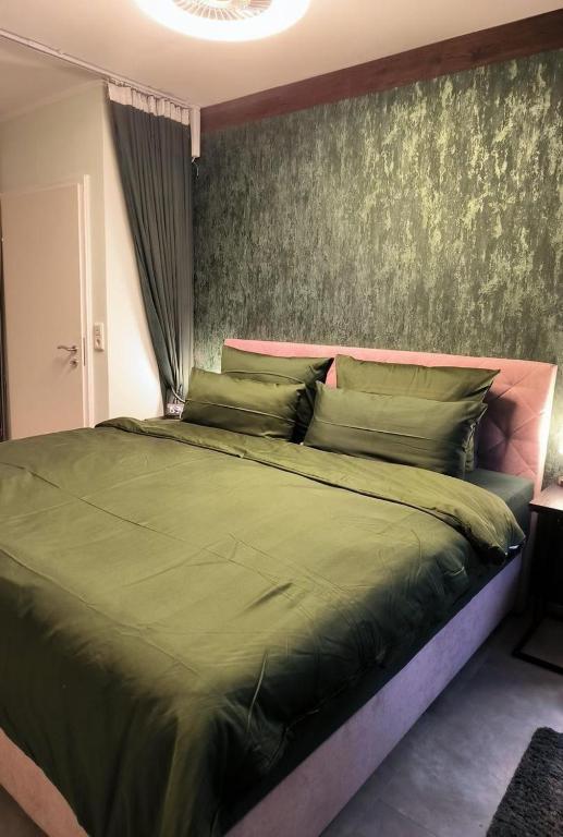 una camera da letto con un grande letto verde con un muro di Harz-High-End-Ferienwohnung-Nicholas a Hahnenklee-Bockswiese