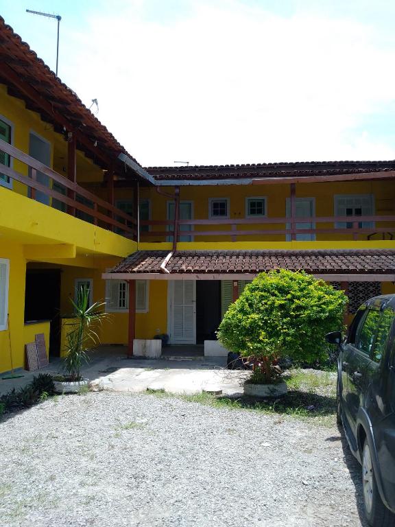 un'auto parcheggiata di fronte a un edificio giallo di Suíte Sunflower 103 a Rio das Ostras