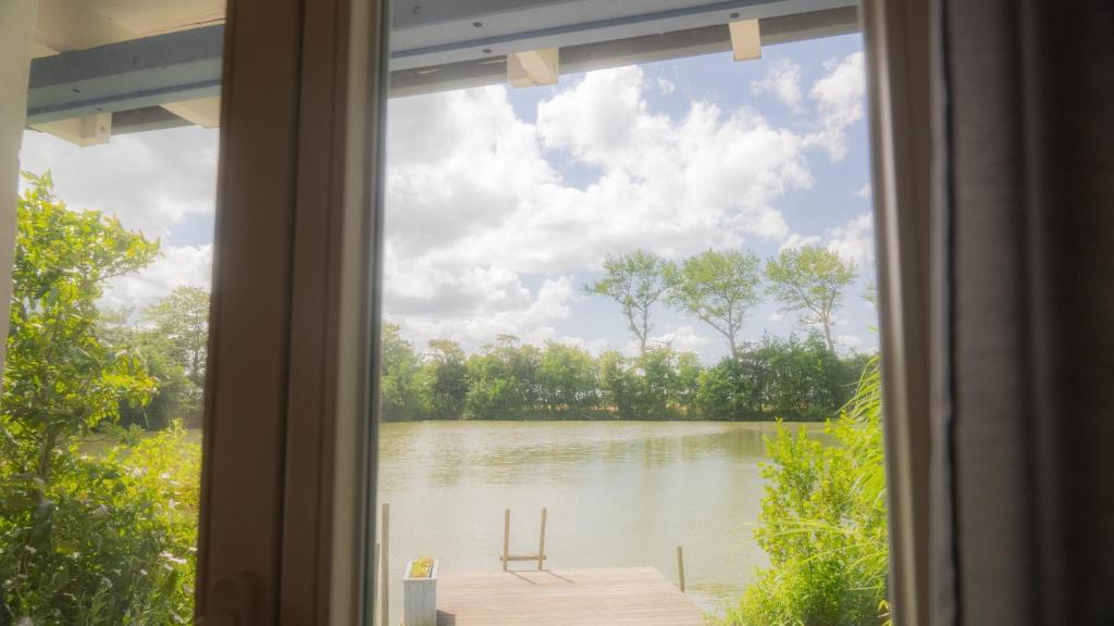 een raam met uitzicht op een meer vanuit een huis bij Schillhörn - Urlaub mit Wasserblick in Neuharlingersiel