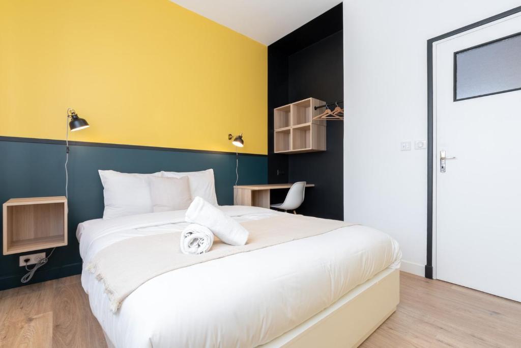 a bedroom with a bed and a yellow wall at Marcq-en-Baroeul - beautiful fully equipped ! 2p in Marquette-lès-Lille