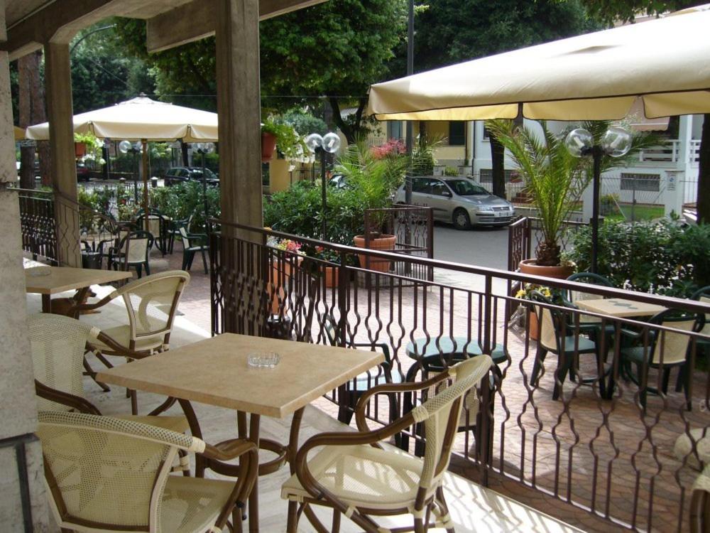 un patio al aire libre con mesas, sillas y sombrillas en Hotel Mucciolini, en Castrocaro Terme