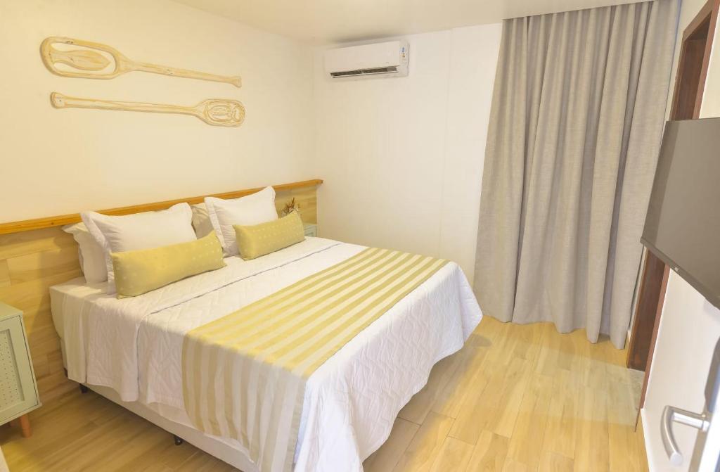 - une chambre avec un grand lit et des oreillers jaunes dans l'établissement Topázio Pousada, à Morro de São Paulo