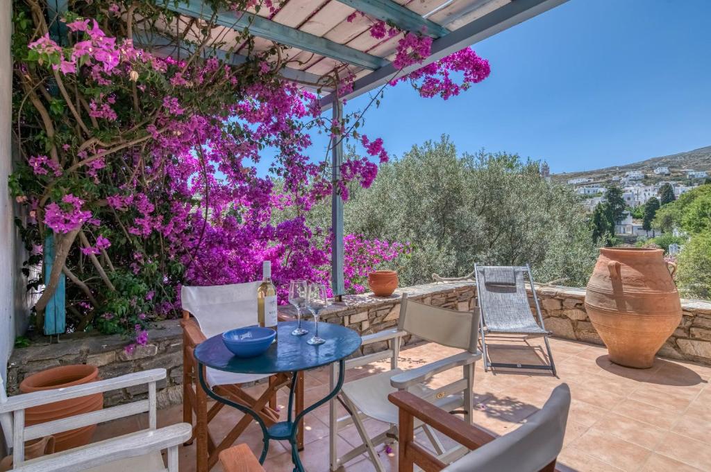 a patio with a table and chairs and purple flowers at Lefkes Village Living in Lefkes