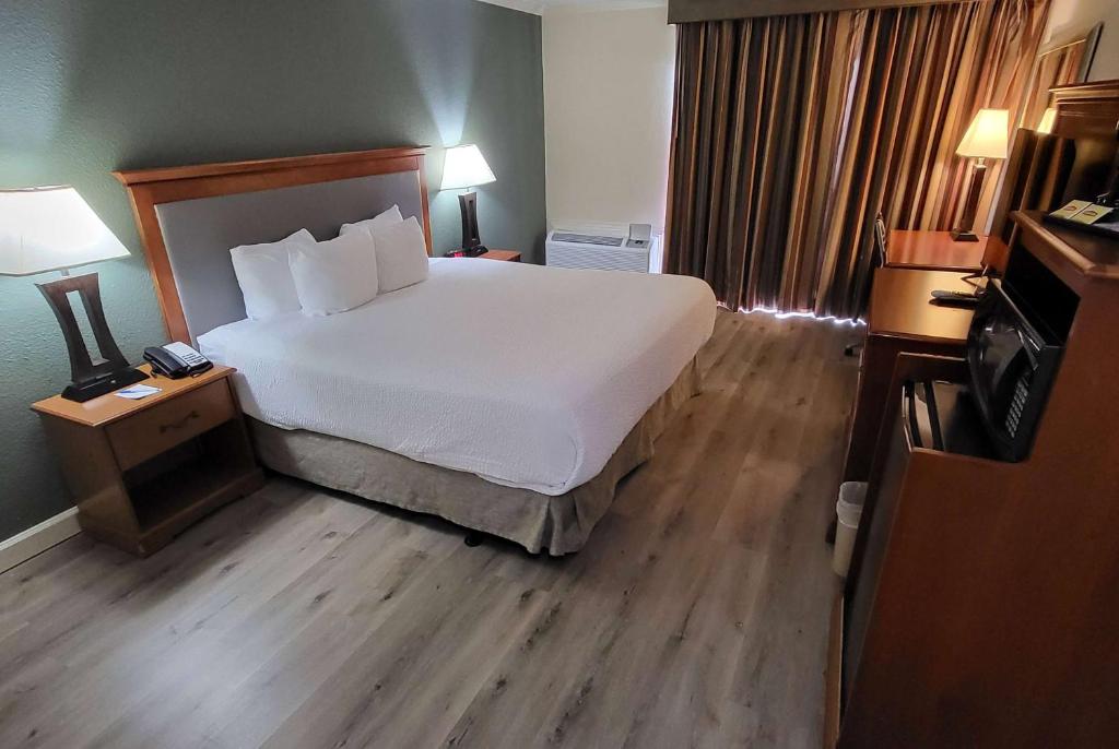a bedroom with a large white bed and wooden floors at Ramada by Wyndham Houston Intercontinental Airport East in Humble