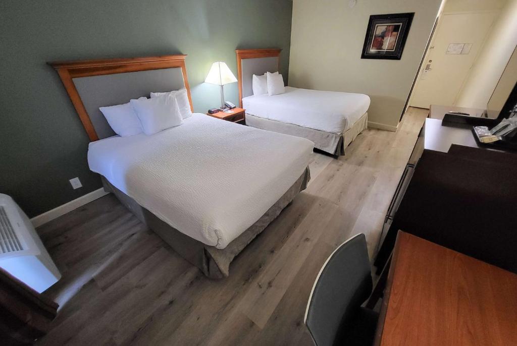 a hotel room with two beds and a desk at Ramada by Wyndham Houston Intercontinental Airport East in Humble